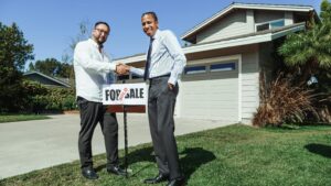 Two men shaking hands in front of a sold house, symbolizing a successful real estate transaction.
